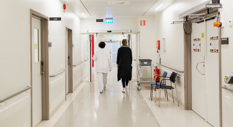 Två personer som går igenom en korridor i ett sjukhus